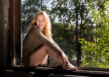 young woman in a short blouse near a broken window in abandoned buildingの写真素材