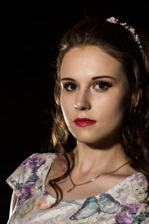 young elegant woman with professional hairstyle poses on a dark background.の写真素材