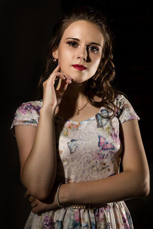 young elegant woman with professional hairstyle poses on a dark background.の写真素材