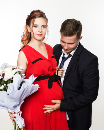 Guy gave a bouquet to a pregnant girlfriend on a date. Couple meeting for date on a light backgroundの写真素材