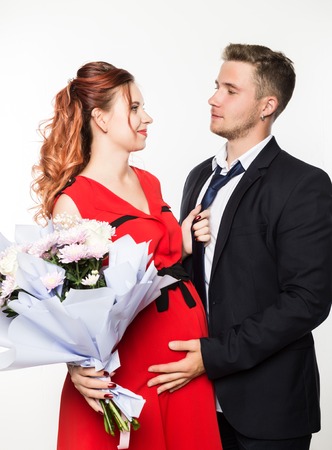 Guy gave a bouquet to a pregnant girlfriend on a date. Couple meeting for date on a light backgroundの写真素材