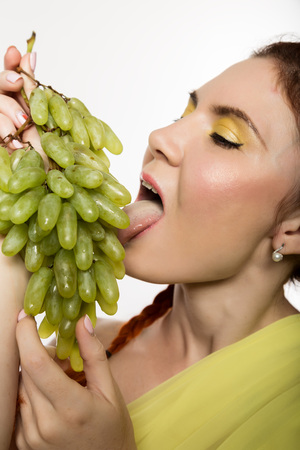 Beautiful redhead woman is eating grapes. concept of healthy eatingの写真素材