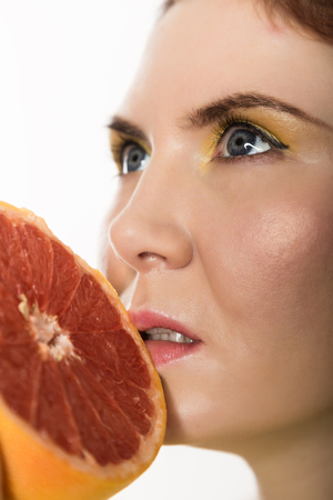 Young redhead woman with grapefruit in her hands studio portrait on a white background. concept of healthy eatingの写真素材