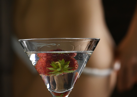 cocktail with strawberry and blured female buttocks in white panties in a dark background. party conceptの写真素材