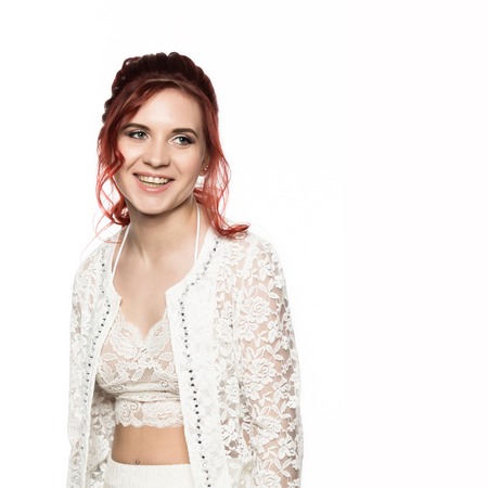 cheerful redhead girl in a transparent blouse with curly hair smiling on a white background. free space for your textの写真素材