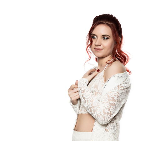 cheerful redhead girl in a transparent blouse with curly hair smiling on a white background. free space for your textの写真素材
