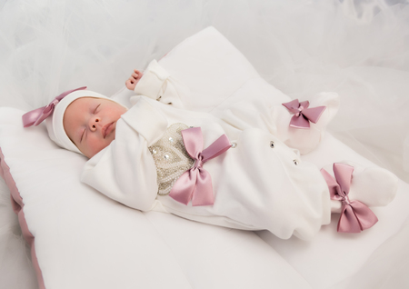 sleeping newborn baby in a wrap lying on a warm blanketの写真素材