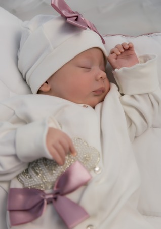 sleeping newborn baby in a wrap lying on a warm blanketの写真素材