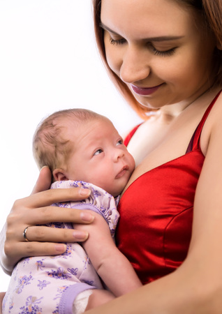 Pretty woman holding a newborn baby in her arms on a white backgroundの写真素材