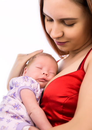 Pretty woman holding a newborn baby in her arms on a white backgroundの写真素材