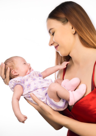 Pretty woman holding a newborn baby in her arms on a white backgroundの写真素材