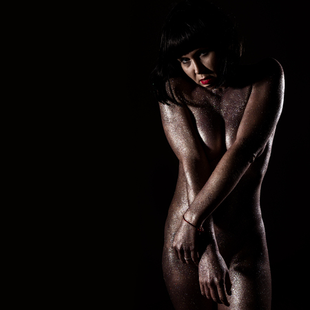 body art with purple sequins on a skin of beautiful nude girl on dark background. free space for your textの写真素材