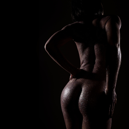 contour of a naked girl on a dark background. beautiful nude girl with body art purple shine skin color. free space for your textの写真素材
