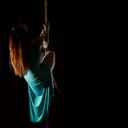 Gorgeous sexy dancer in night club. woman in a long turquoise dress with a slit on a dark background. free space for your text.の写真素材