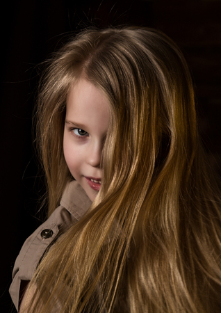 beautiful lovely little blonde girl with different emotions on a dark backgroundの写真素材