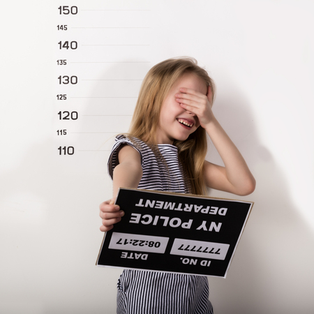 Young beautiful blonde child with a sign covers his face with his hand, Criminal Mug Shotsの写真素材