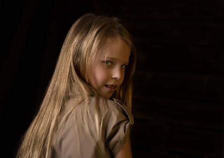 beautiful lovely little blonde girl with different emotions on a dark backgroundの写真素材