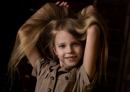 beautiful lovely little blonde girl with different emotions on a dark backgroundの写真素材