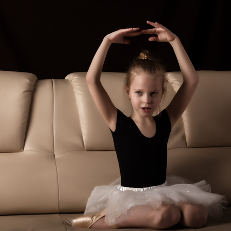 little ballerina in pointe sits and resting on the sofa. cute ballerina in the dance class is studying ballet. Classical dance, balletの写真素材