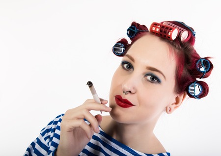 funy housewife with curlers smokes a cigarette. smoking break for sexy lady. free space for your textの写真素材