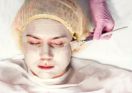 Cosmetologist applying facial mask to problem skin. young woman having skin procedures cleaningの写真素材