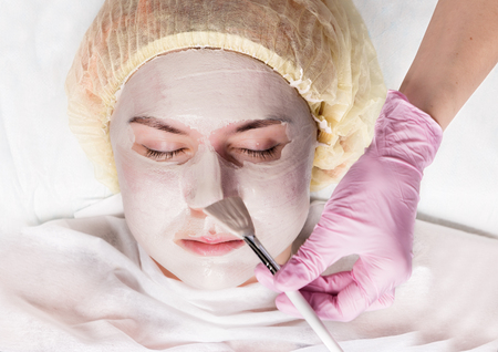 Cosmetologist applying facial mask to problem skin. young woman having skin procedures cleaningの写真素材