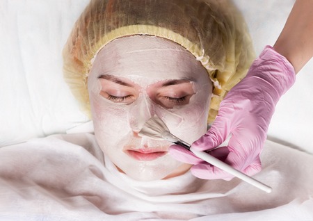 Cosmetologist applying facial mask to problem skin. young woman having skin procedures cleaningの写真素材