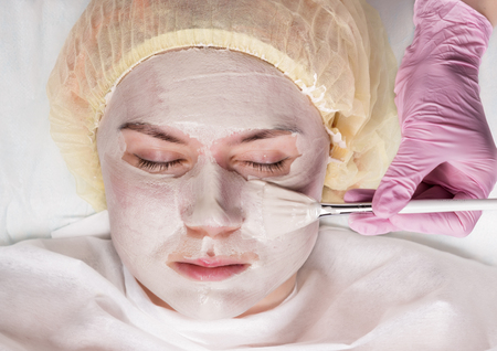 Cosmetologist applying facial mask to problem skin. young woman having skin procedures cleaningの写真素材