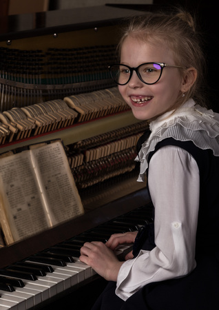 strict little girl in a big glasses playing the piano, child imitates teacherの写真素材