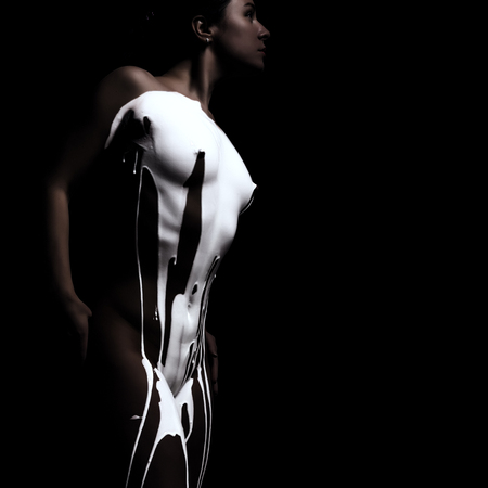 silhouette of seductive woman on a dark background. Nude athletic female body. milk drips on the body. free space for your text.の写真素材