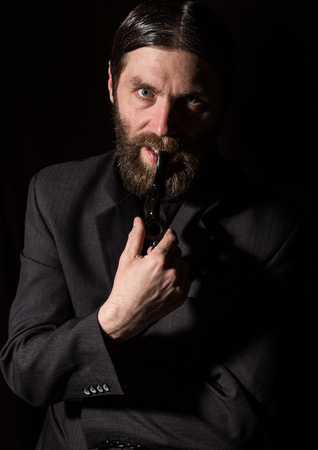 vintage handsome bearded man with a smoking pipe on a dark backgroundの写真素材