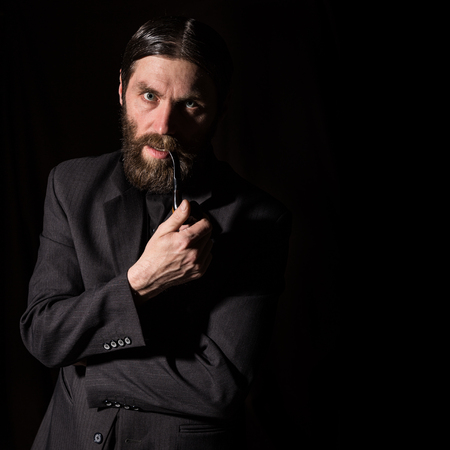 vintage handsome bearded man with a smoking pipe on a dark background. free space for your textの写真素材