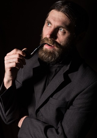 vintage handsome bearded man with a smoking pipe on a dark backgroundの写真素材