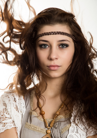 Young beautiful hippie boho woman with fluttering hair having fun poses on a white backgroundの写真素材
