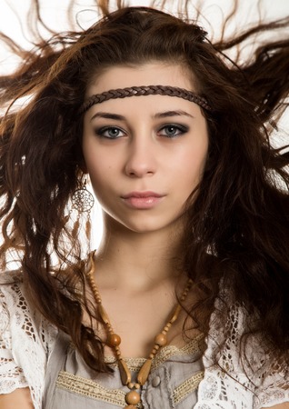 Young beautiful hippie boho woman with fluttering hair having fun poses on a white backgroundの写真素材