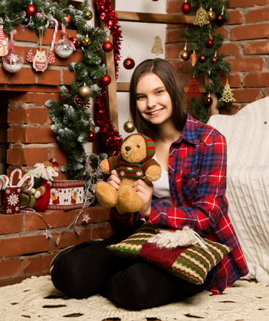 teenag girl sitting near the fireplace with Christmas decorations and toysの写真素材