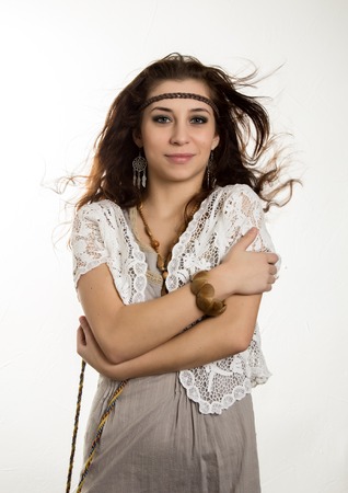 Young beautiful hippie boho woman with fluttering hair having fun poses on a white backgroundの写真素材