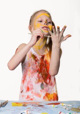 Little schoolgirl. Cute little girl painter draws on the table and on himself on her clothes. slow motionの写真素材