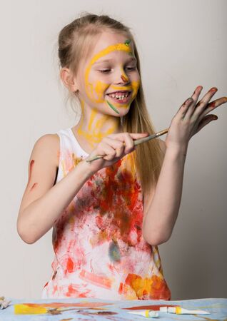 Cute little girl painter draws on the table and on himself on her clothes. slow motionの写真素材