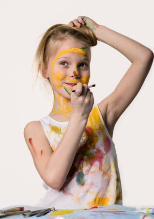 Little schoolgirl. Cute little girl painter draws on the table and on himself on her clothes. slow motionの写真素材