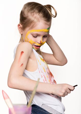 Cute little girl painter draws on the table and on himself on her clothes. slow motionの写真素材