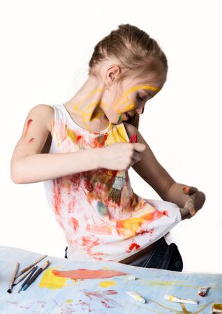 Cute little girl painter draws on the table and on himself on her clothes. slow motionの写真素材