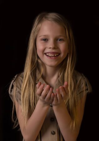 beautiful lovely little blonde girl with different emotions on a dark backgroundの写真素材