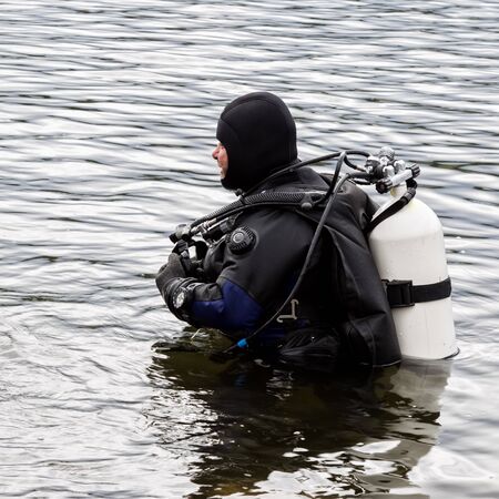 scuba diver enters the mountain lake water. practicing techniques for emergency rescuers. immersion in cold waterの写真素材