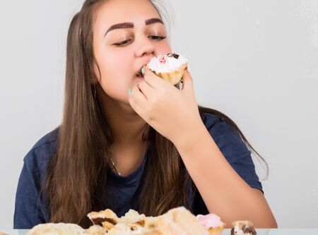Young woman eating cupcakes with pleasure after a dietの写真素材