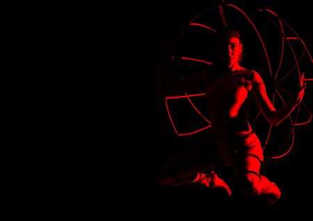 silhouette of sexy woman in red light on a dark background. leggy woman in a bodysuit with metal rings. free space for textの写真素材
