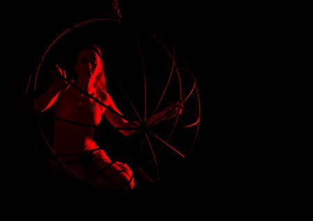 silhouette of sexy woman in red light on a dark background. leggy woman in a bodysuit with metal rings. free space for textの写真素材
