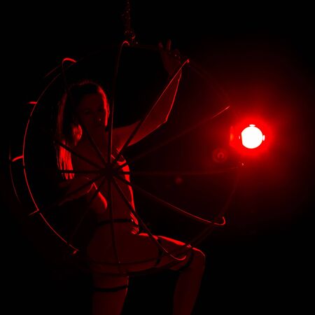 silhouette of sexy woman in red light on a dark background. leggy woman in a bodysuit with metal ringsの写真素材
