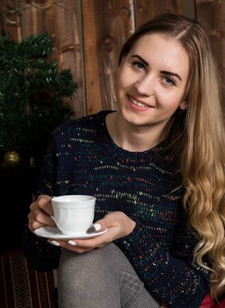 Beautiful young woman in a knitted sweater with cup of coffeeの写真素材