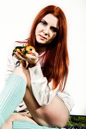 young redhead woman eats citrus orange fruit having funの写真素材